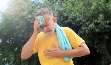 Ein älterer Herr greift sich vor Hitzeerschöpfung an die Brust